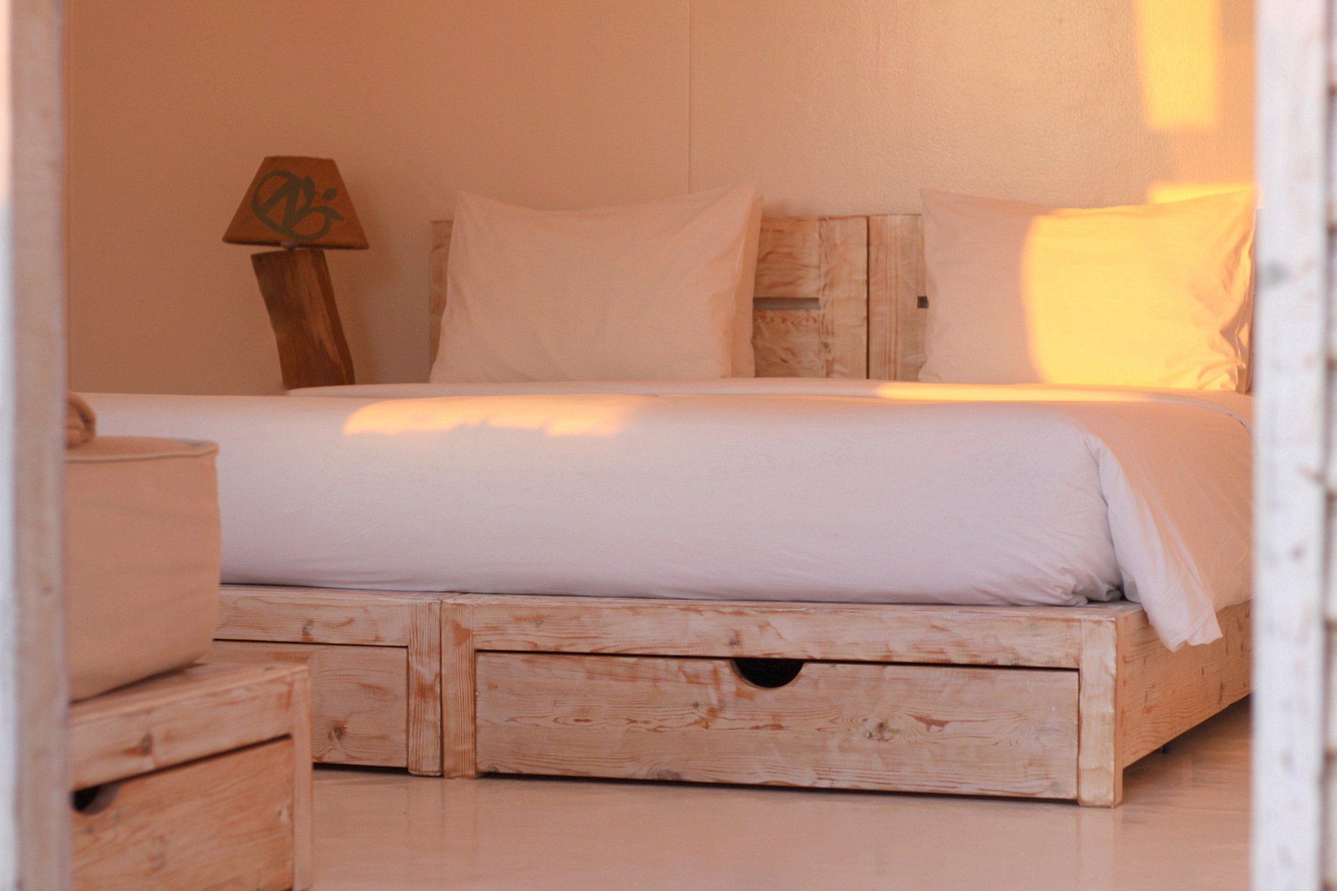 Une chambre avec un lit, une table de nuit, une lampe et des tiroirs.
