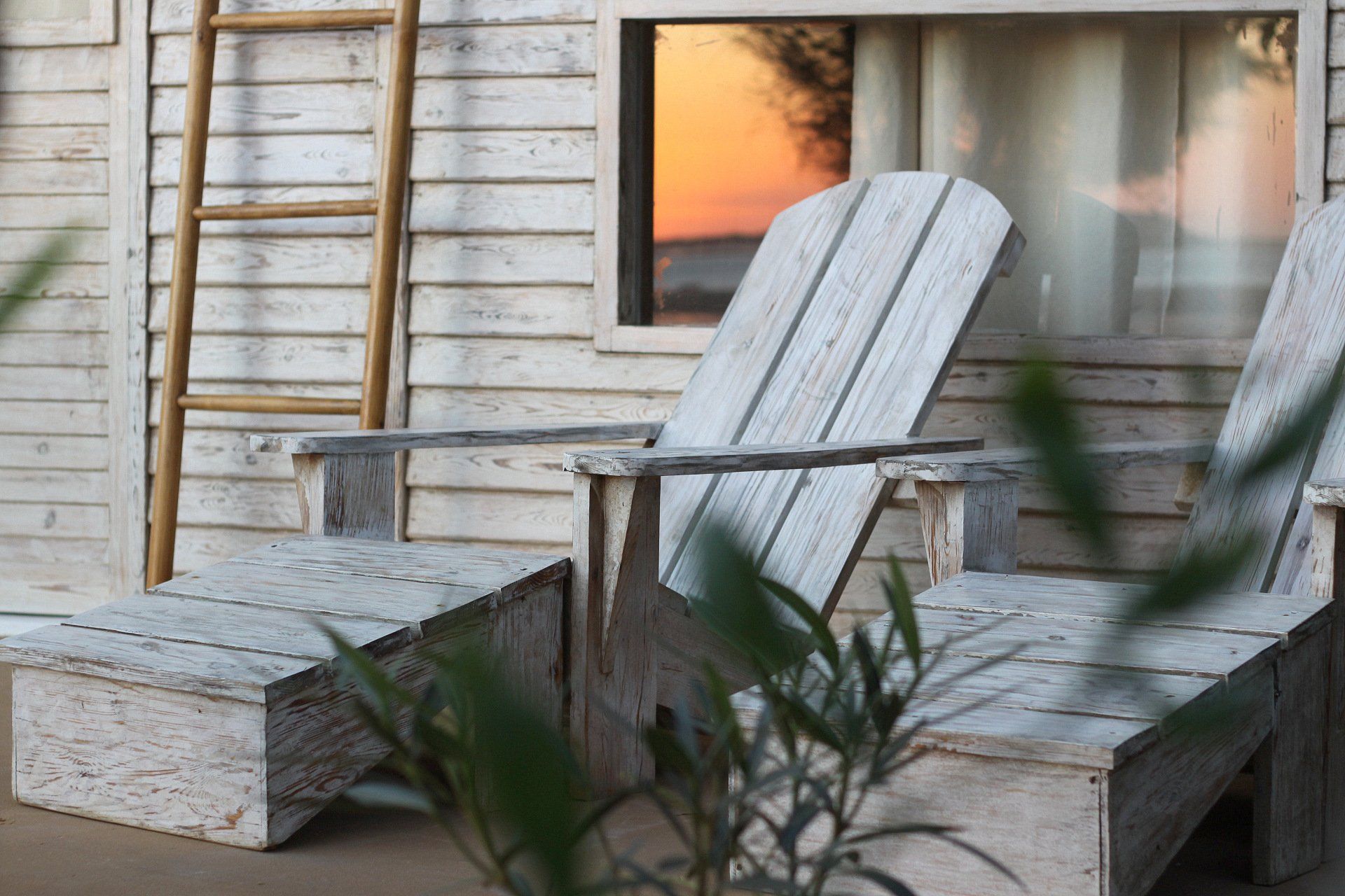 Deux chaises en bois blanc sont assises devant une maison blanche.