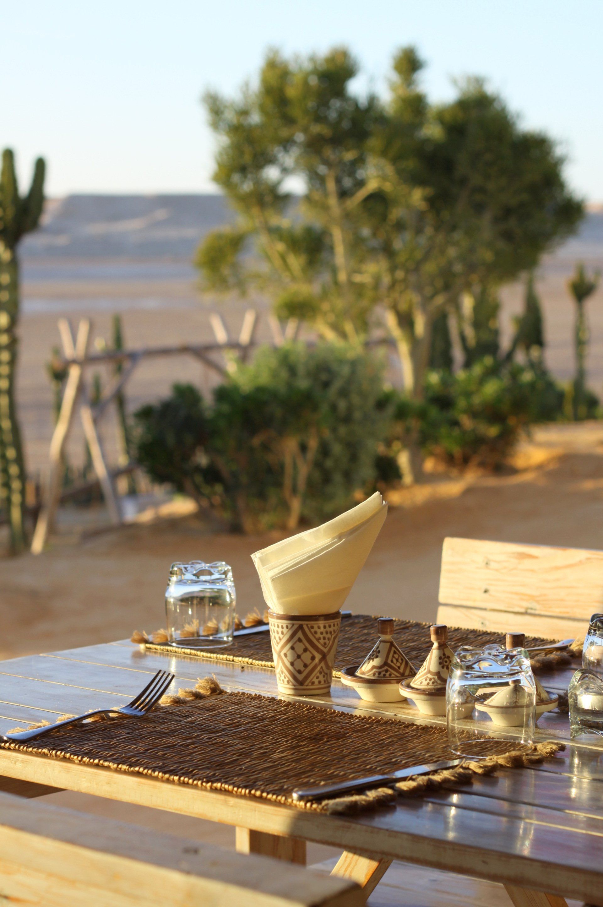 Une table en bois avec une serviette et des verres dessus dans le désert.