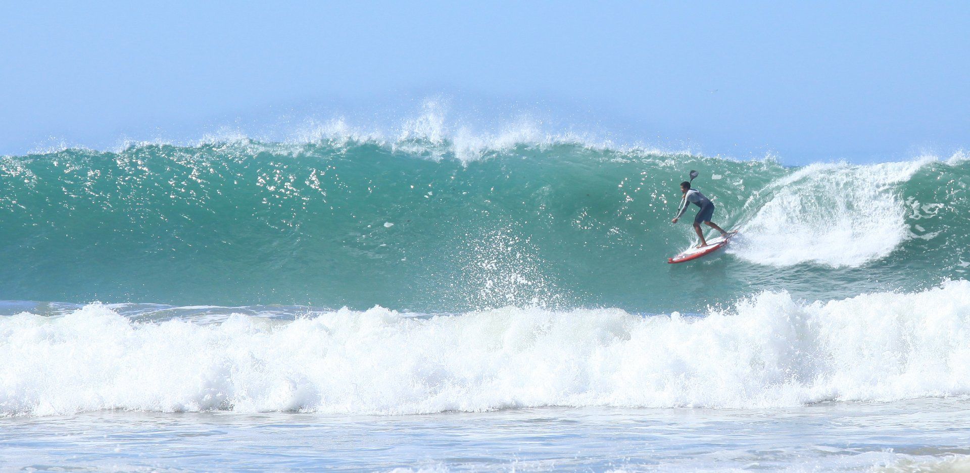 Un homme surfe sur une vague sur une planche de surf dans l'océan.