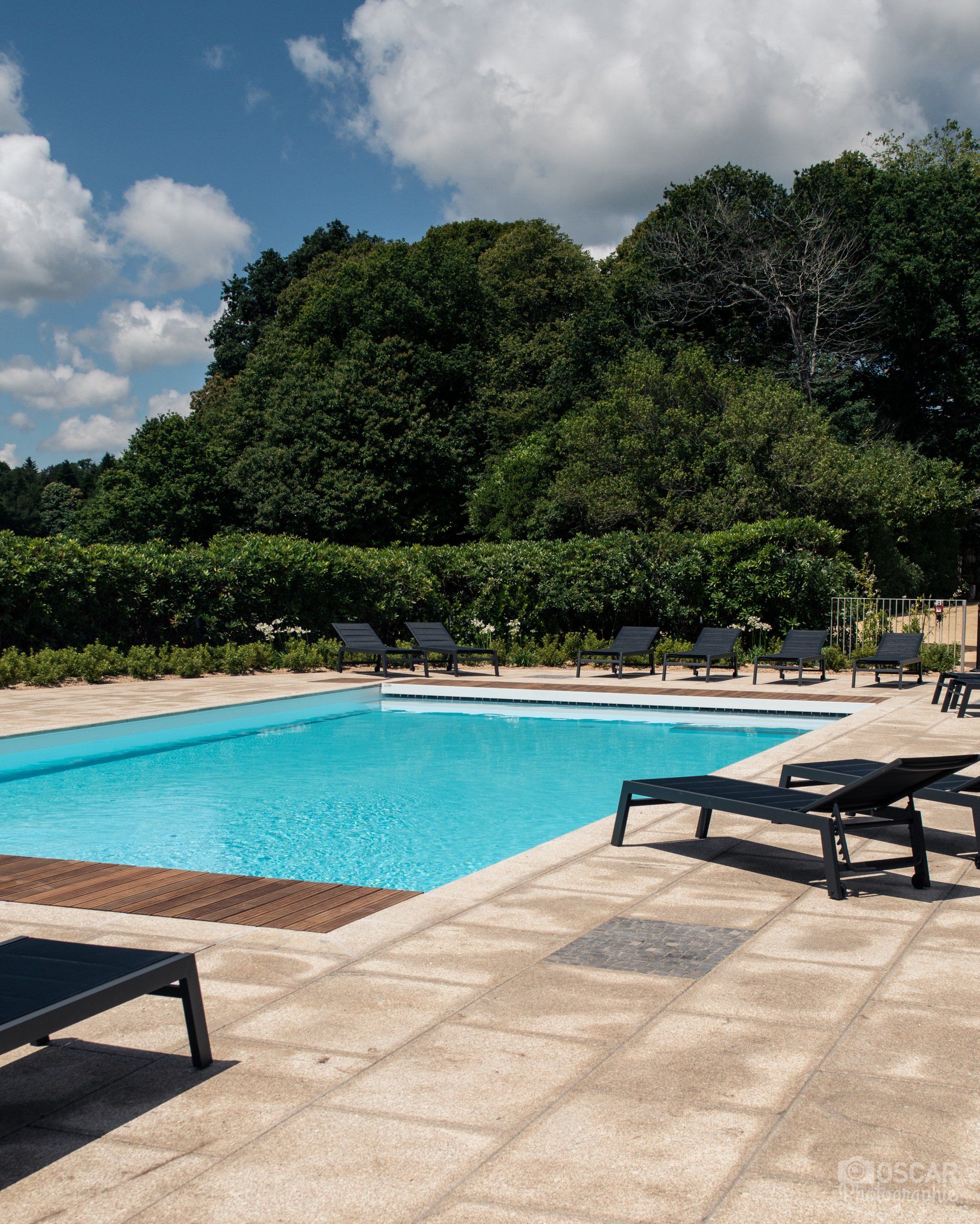 Une grande piscine entourée de chaises et d'arbres