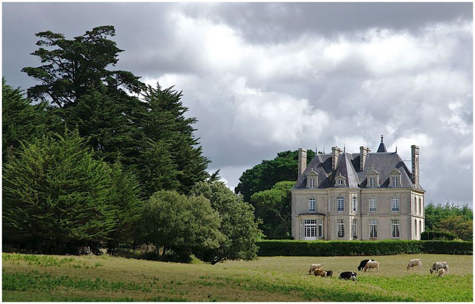 Une grande maison se trouve au milieu d'un champ herbeux