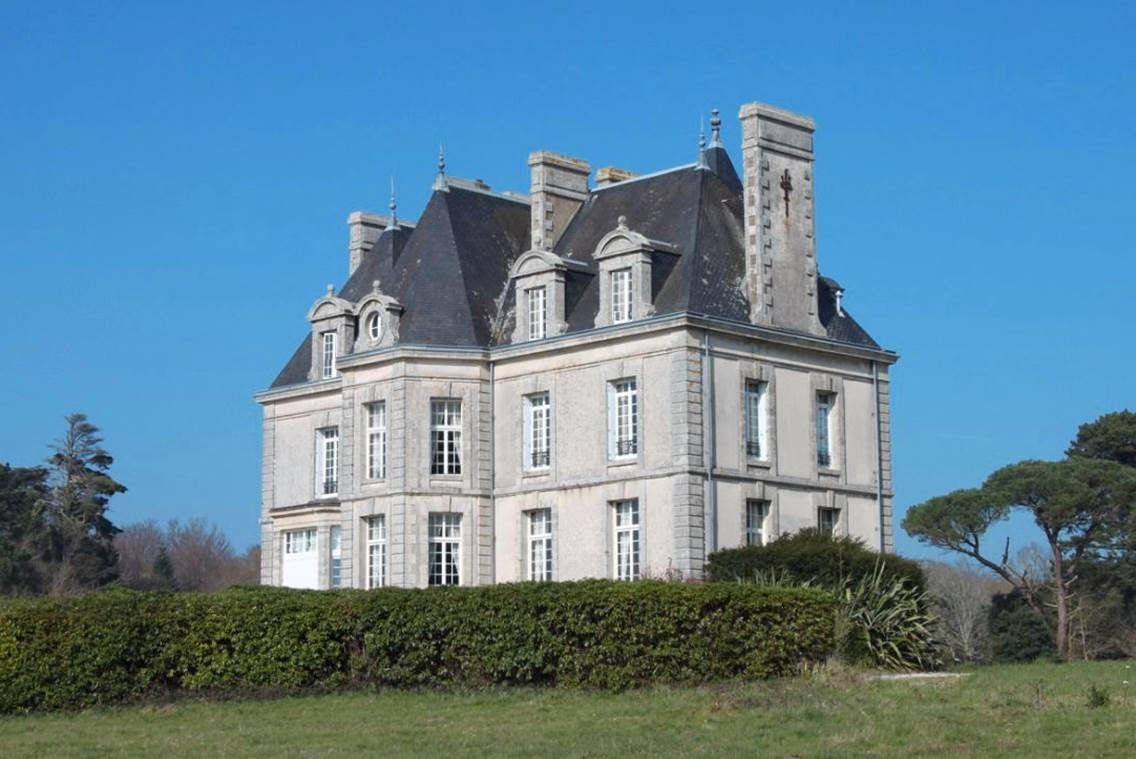Un grand château est assis au milieu d'un champ herbeux.
