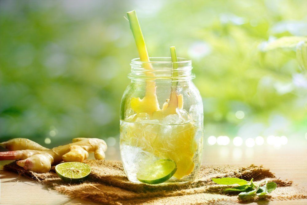 Un verre d'eau à la citronnelle avec de la glace et une paille sur une table.