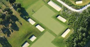 Une vue aérienne d'un parcours de golf entouré d'arbres.