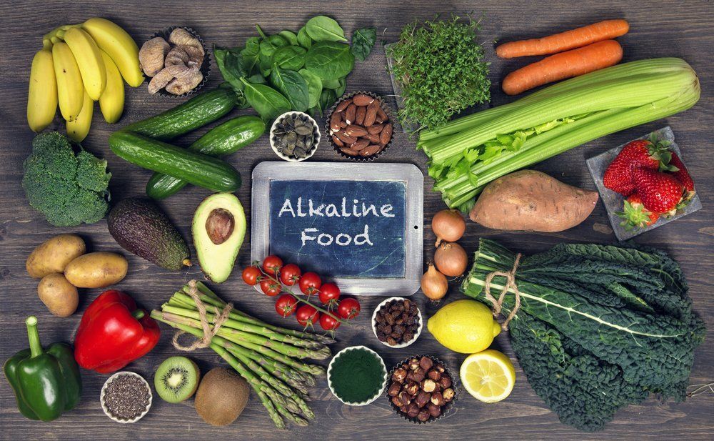 Une table garnie d'une variété de fruits et de légumes et d'un panneau indiquant « aliments alcalins ».