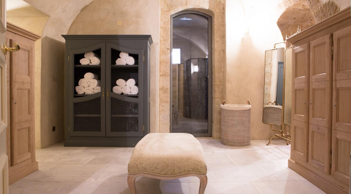 Un vestiaire avec un banc et une armoire remplie de serviettes.