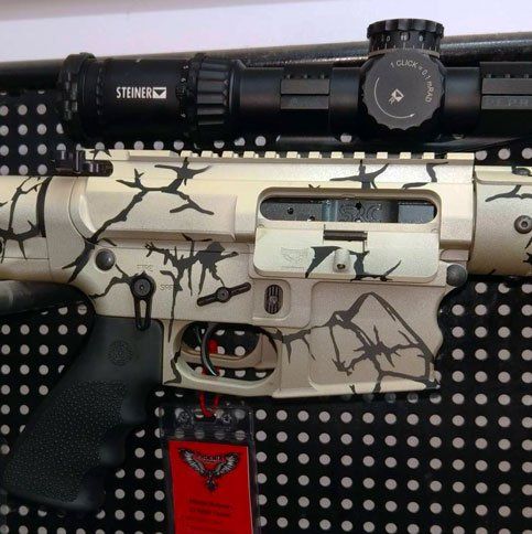 Cream and black patterned rifle with scope, black grip, and red tag.