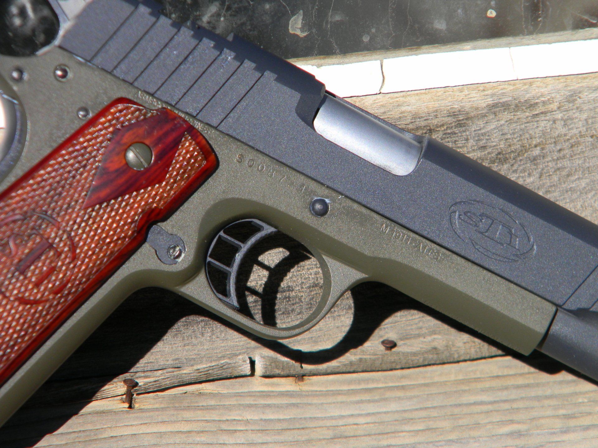 Close-up of an olive green and black handgun with a red-brown grip.