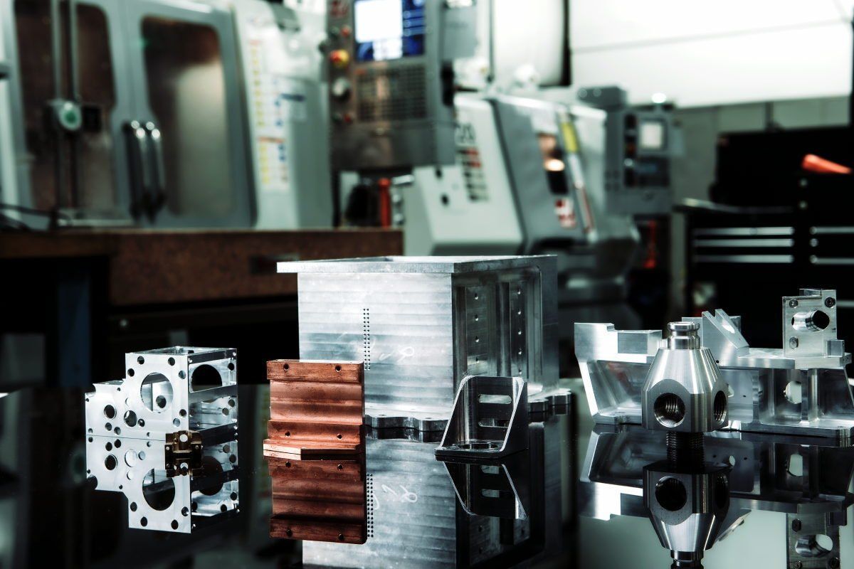 Machining shop interior with metal components in the foreground, machinery in the background.