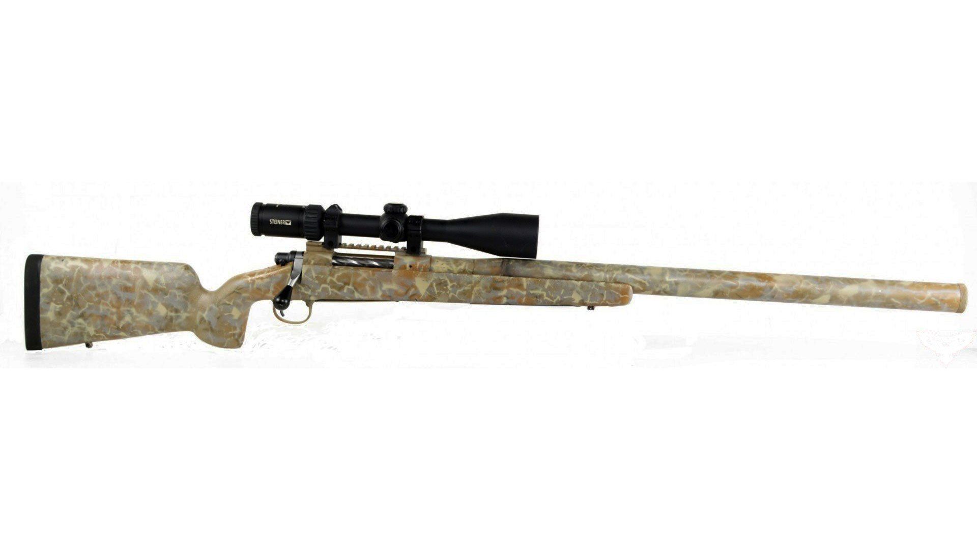 A camouflage-patterned bolt-action rifle with a mounted scope, on a white background.