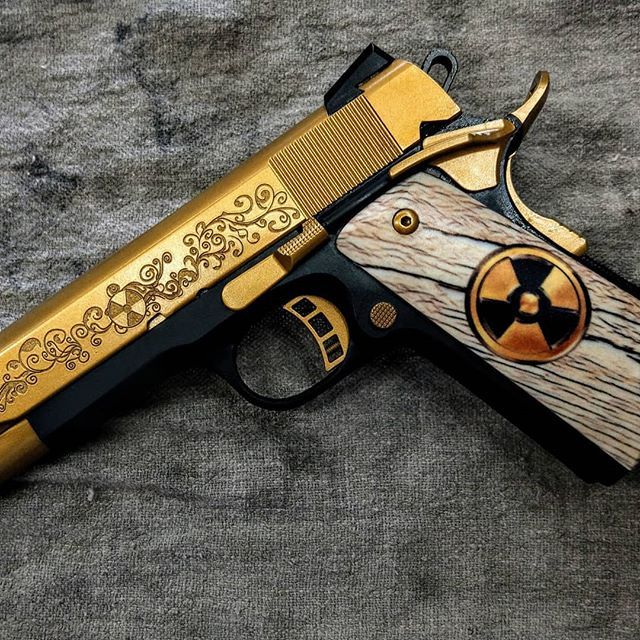 Gold and black handgun with ornate carvings, wood grips with radiation symbol.