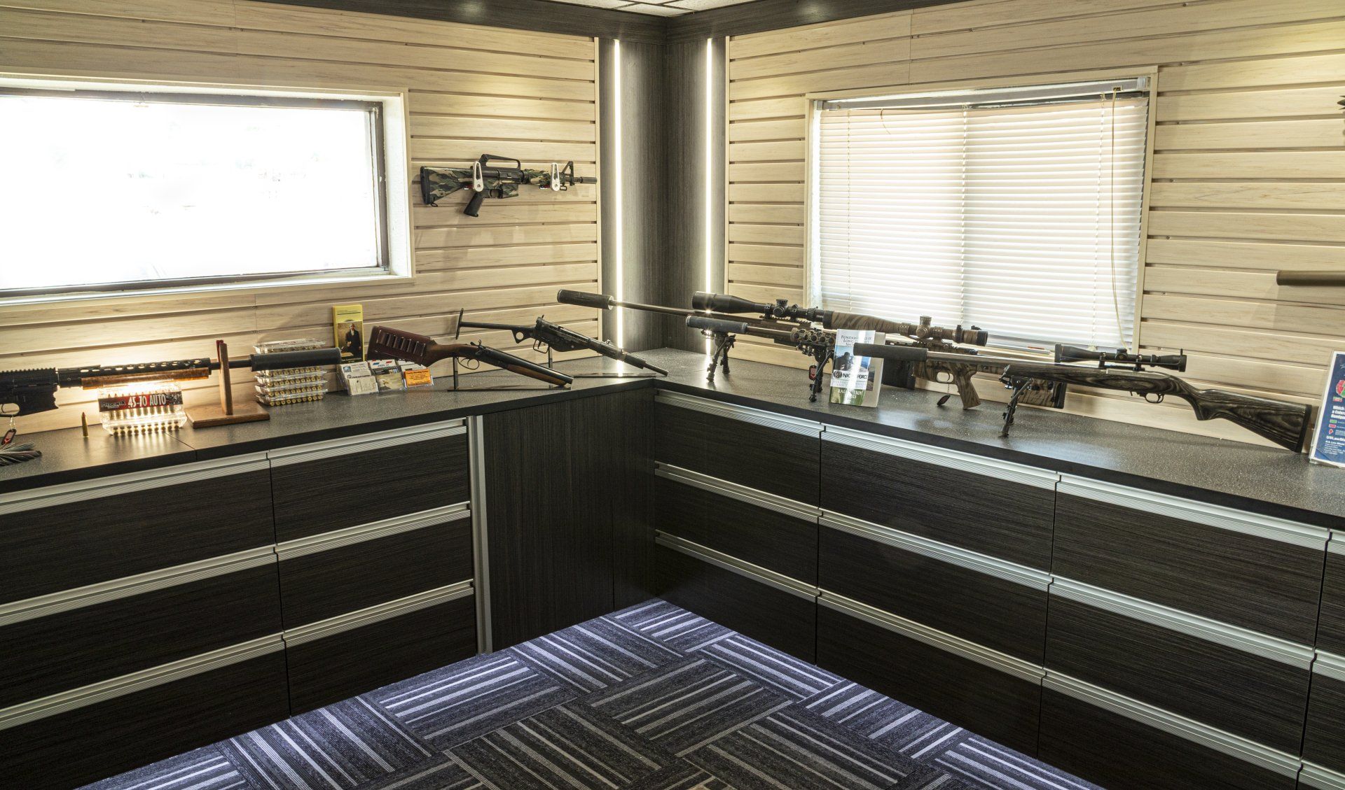 Guns displayed on a counter and wall in a room with a window.