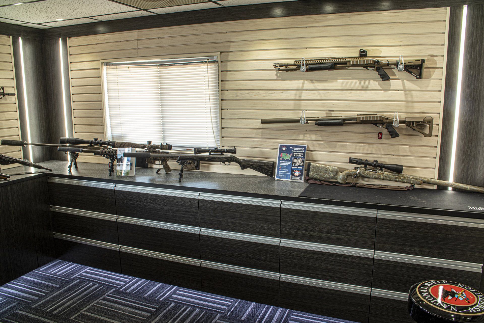Firearms displayed on a counter and wall inside a store.
