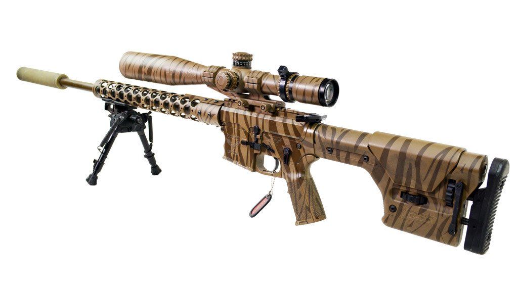 A camouflaged sniper rifle with a scope and bipod on a white background.