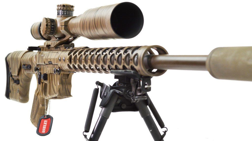 Camouflage-patterned sniper rifle with scope and bipod.