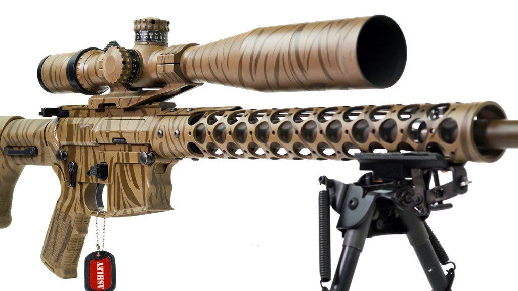 Camouflage rifle with scope and bipod on white background.