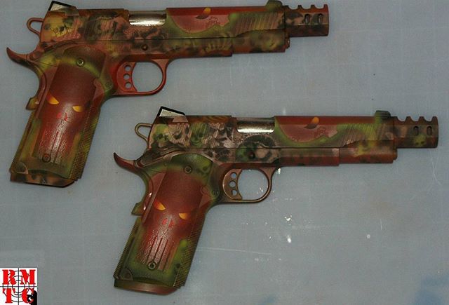 Two custom-painted handguns with a camouflage design in shades of brown, green, and red.