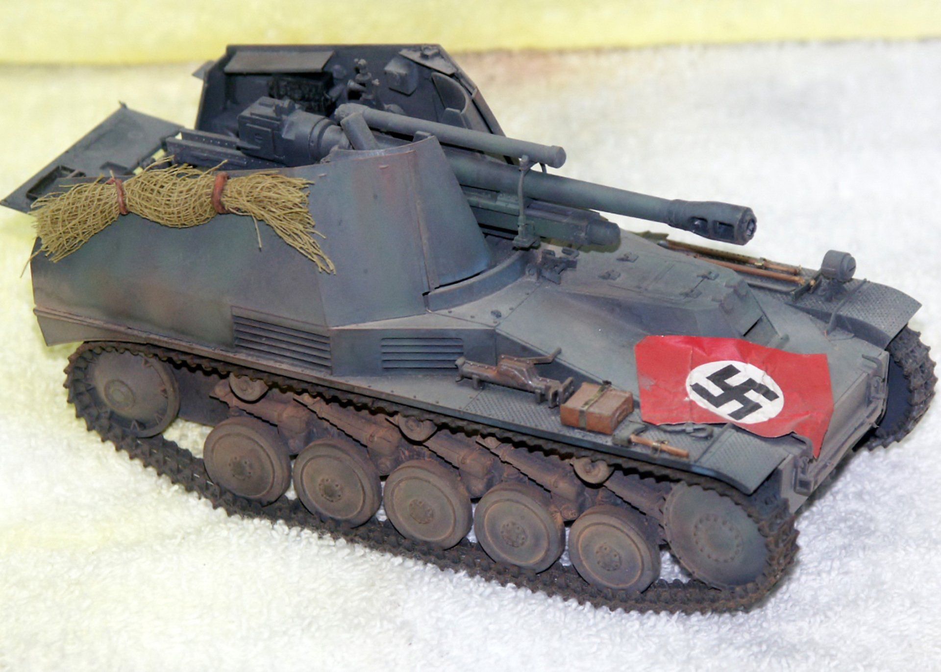 Model of a German tank destroyer with a large gun and swastika flag, painted in gray and brown.