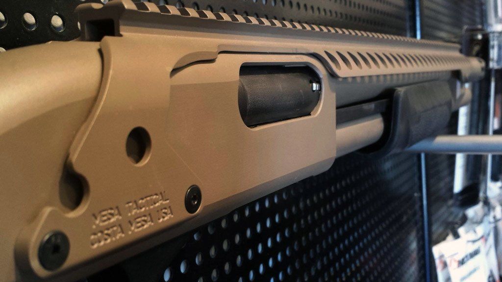 Tan shotgun with black accents, side view. 