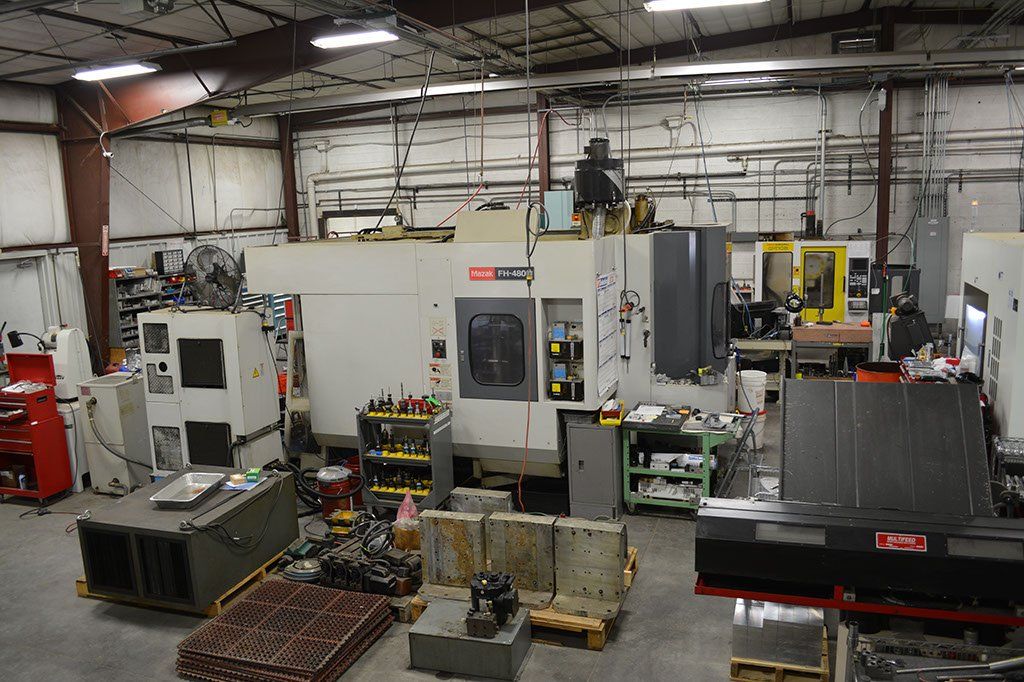 A workshop with various industrial machines, tools, and metal parts.