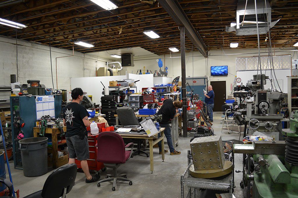 Workshop interior with several people working on machinery and equipment.