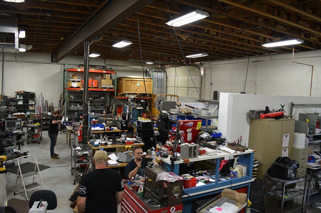 Workshop interior with several gunsmiths working on various fiearm projects.