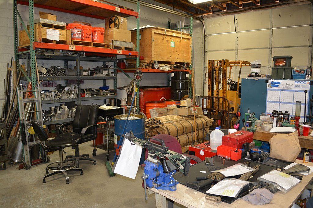 Cluttered workshop with shelves of parts, various tools, and a desk.