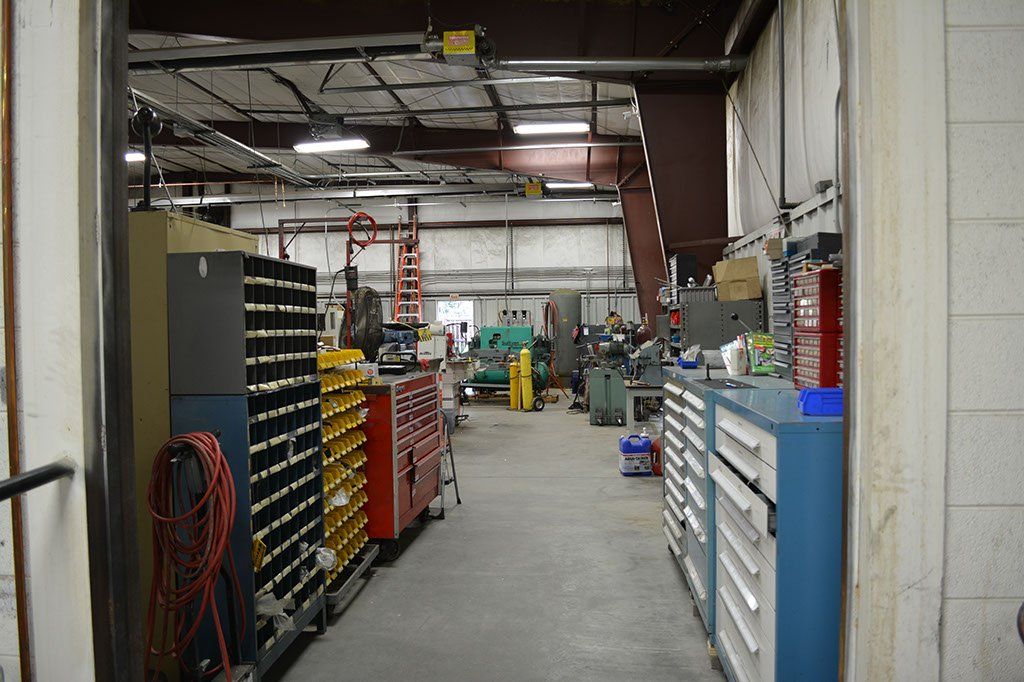 Interior view of a workshop, with tools, cabinets, and machinery visible down a long hallway.