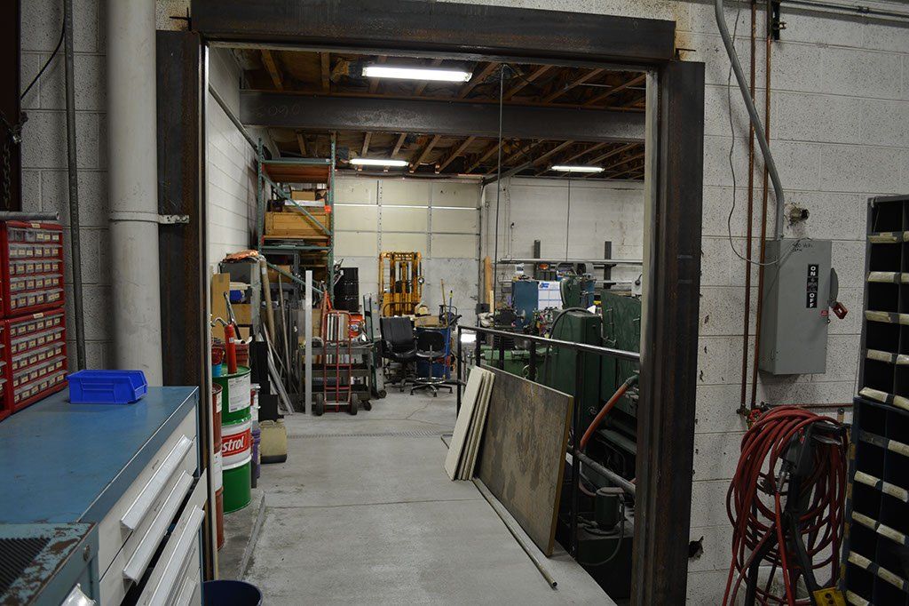 Open doorway into a workshop filled with tools, equipment, and a forklift.
