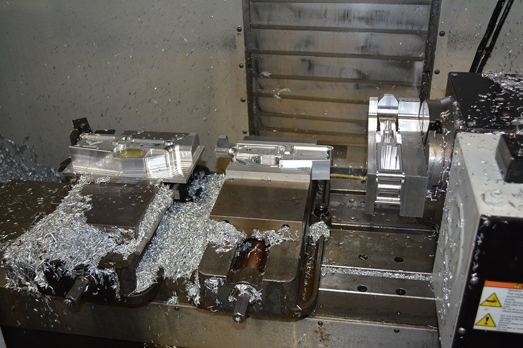 CNC milling machine with metal parts being machined, covered in metal shavings.