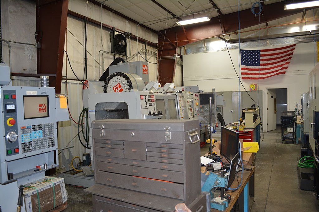 Workshop interior with machinery, tools, and an American flag.