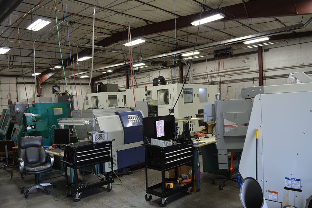 Machine shop interior with multiple CNC machines, tools, and work carts.