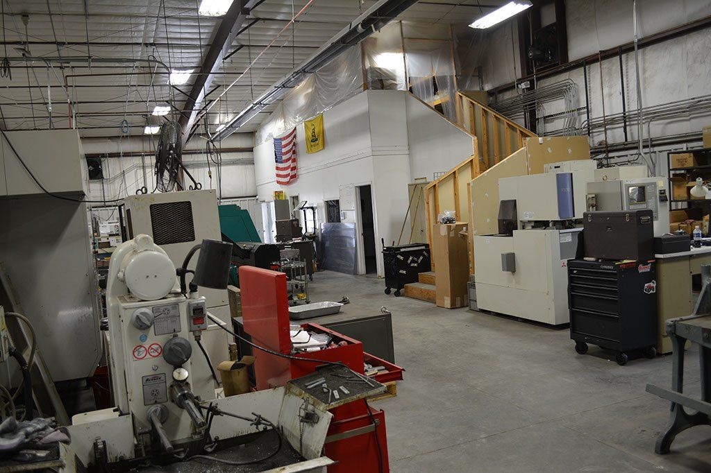 An industrial workshop with machinery, tools, and a second-story office area.
