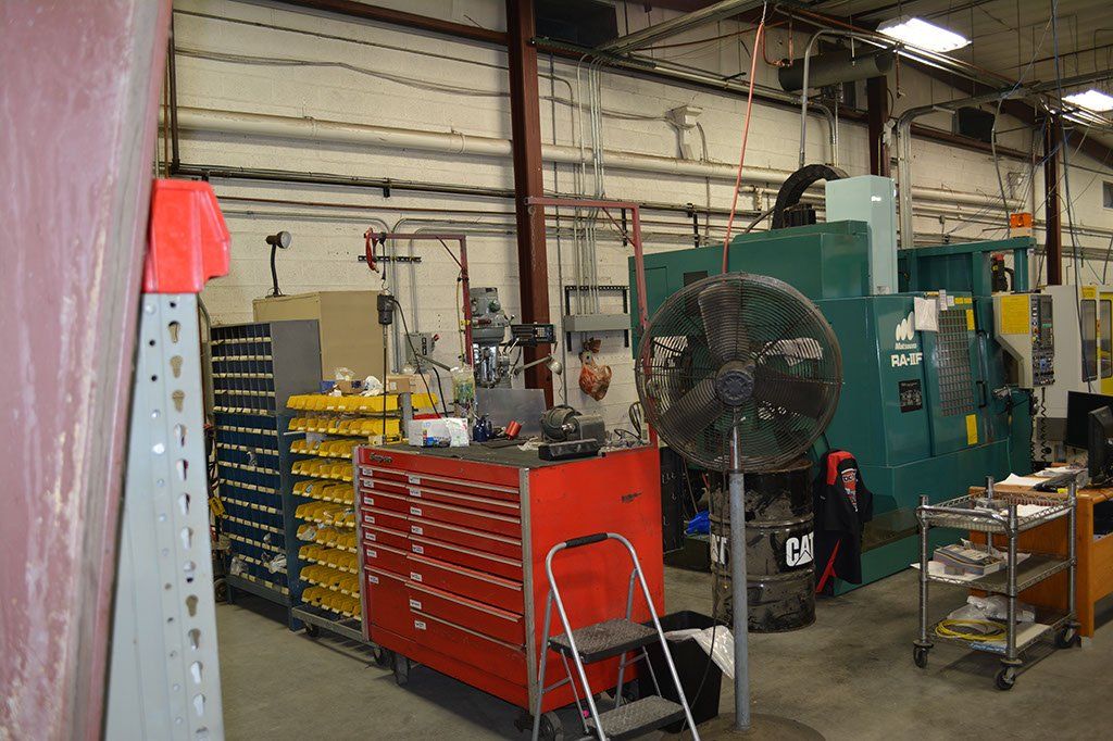 Workshop interior with machinery, toolboxes, and a large fan.