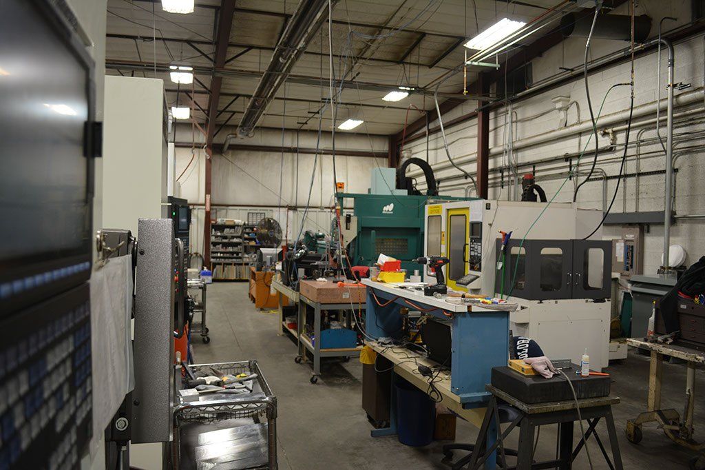 Inside a machine shop with various industrial machines, tools, and a person.