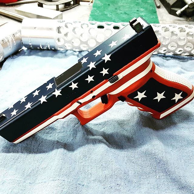 Patriotic-themed Glock handgun with American flag design: blue slide, red grip, and white stars and stripes.