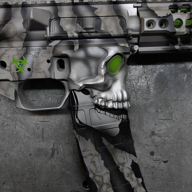 Custom painted AR-15 rifle with skull design and green eye accents in a camouflage pattern.