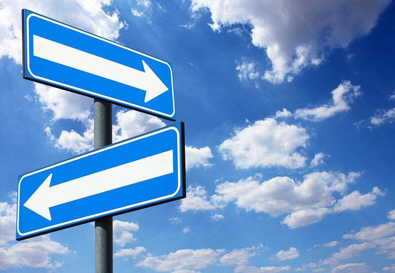 Due segnali stradali direzionali blu con frecce bianche contro un cielo nuvoloso.