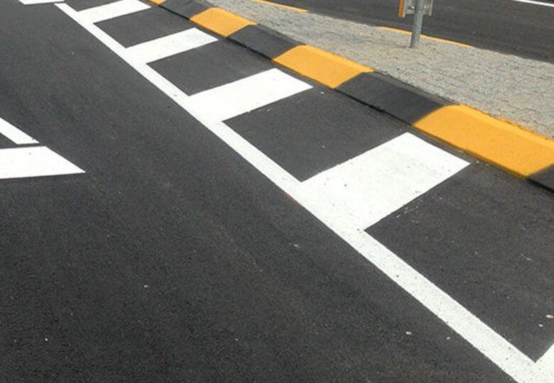 Segnaletica stradale gialla e bianca su asfalto scuro, che indica una rampa per disabili