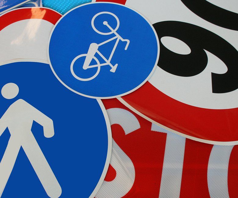 Segnali stradali blu per ciclisti, pedoni e limiti di velocità, sovrapposti su uno sfondo rosso e bianco.