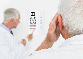 Pediatrician ophthalmologist with senior patient pointing at eye chart — eye exams in Yorktown, VA Pediatrician ophthalmologist with senior patient pointing at eye chart — eye exams in Yorktown, VA
