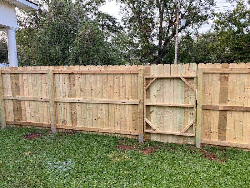 Wooden fence with a gate in a grassy yard.