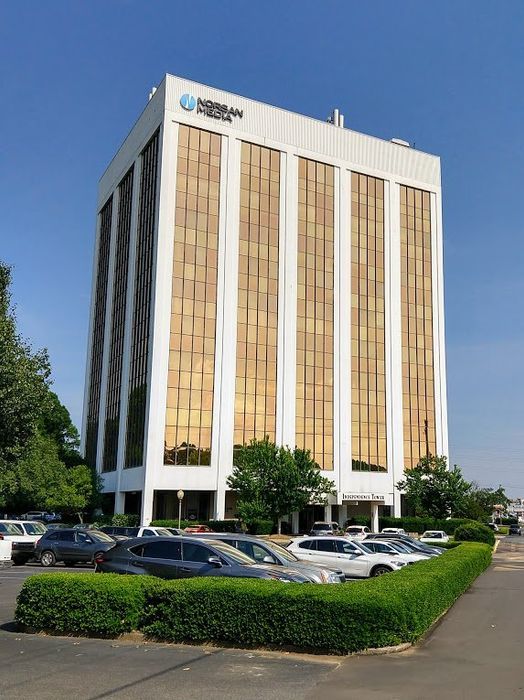 AAC Office Building — Charlotte, NC — AAC Insurance Group A tall, white, multi-story office building with golden-tinted windows stands above a parking lot and manicured hedges.