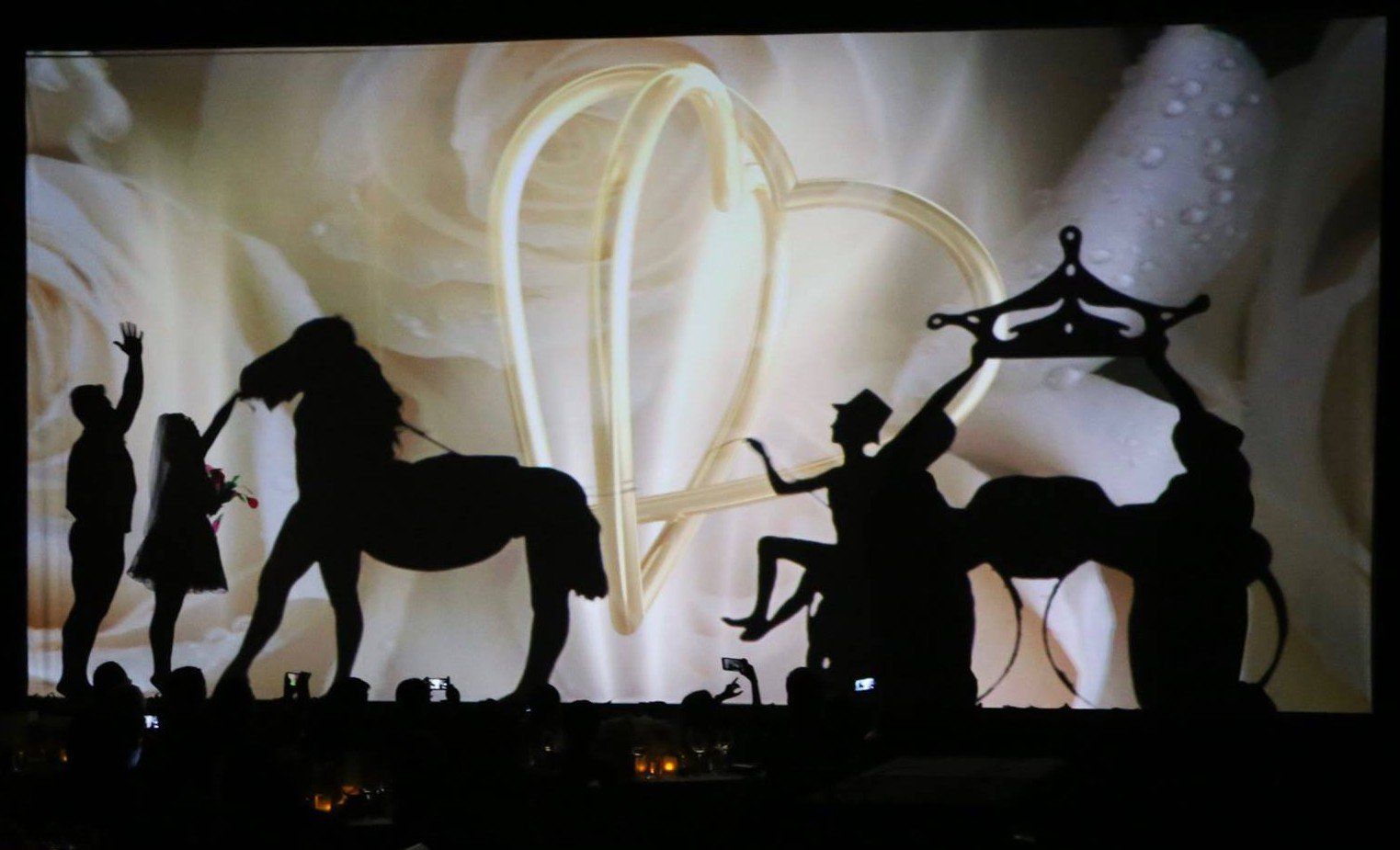 Silhouettes of circus performers and a horse against a warm, glowing backdrop