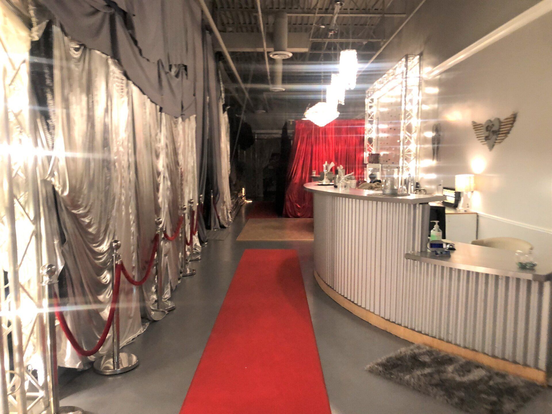 Red carpet walkway beside silver drapes and a decorated reception counter in a dim hallway.