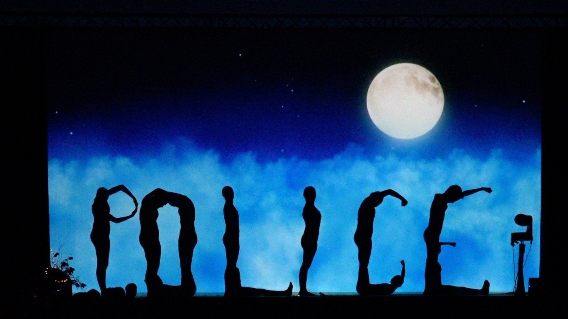 Policemen silhouettes spelled by figures under a full moon at night