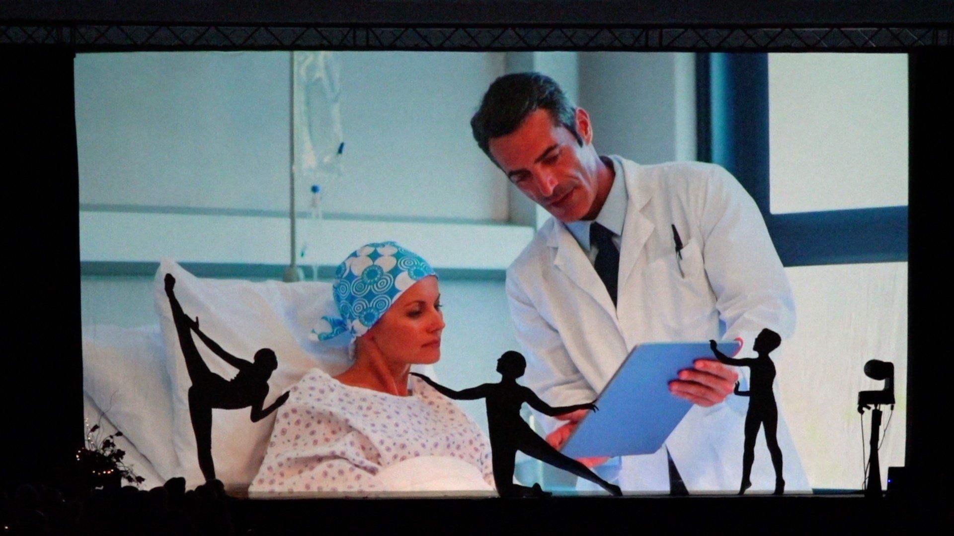 Doctor shows a blue folder to a patient in a hospital room.