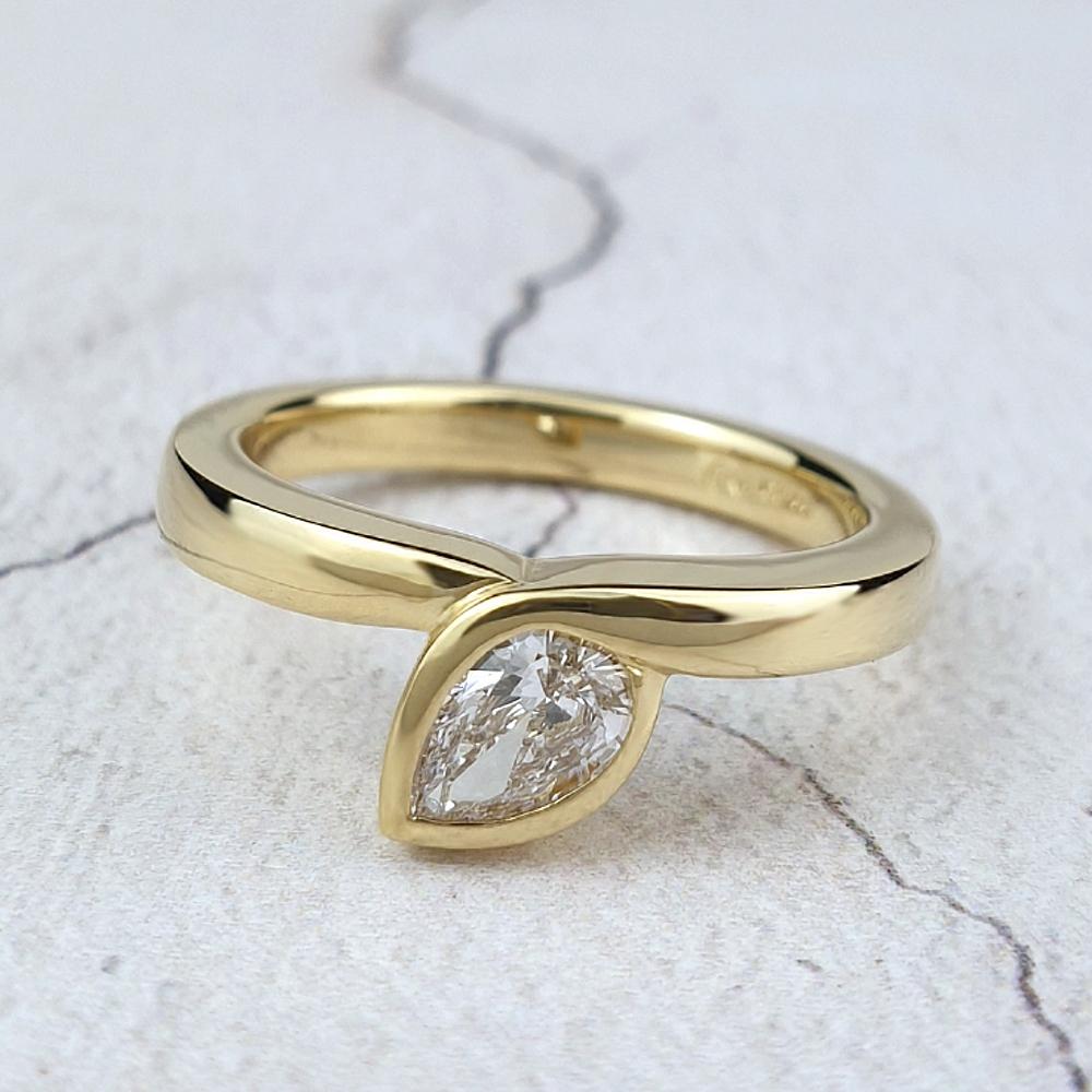 A pear-shaped diamond set diagonally in an 18ct yellow gold infinity ring