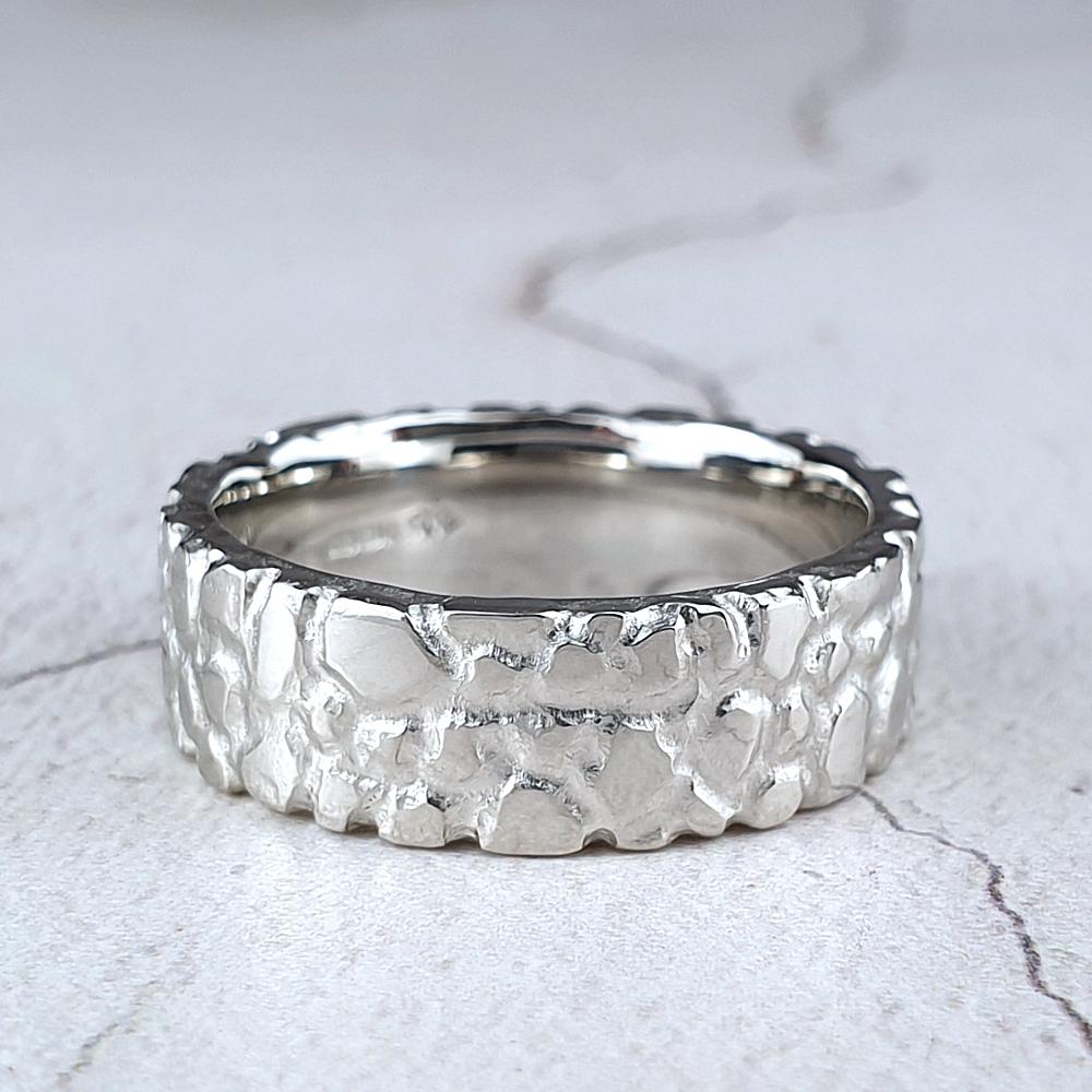 A wide platinum band with a nugget texture